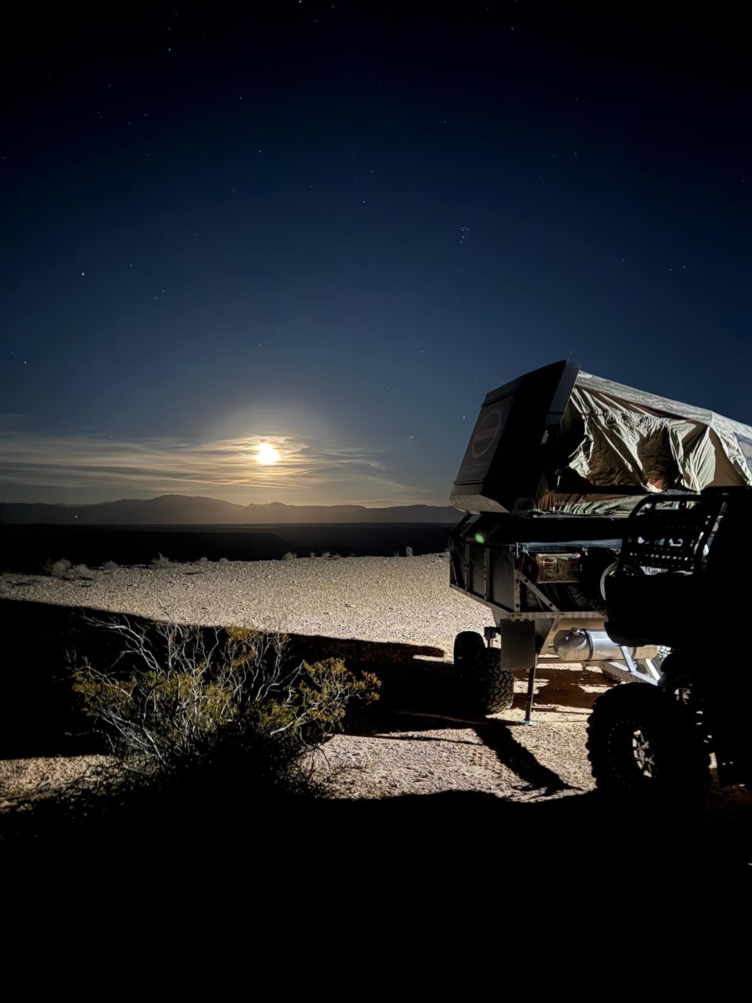 Camp Mansion rooftop trailer under a full moon in the desert